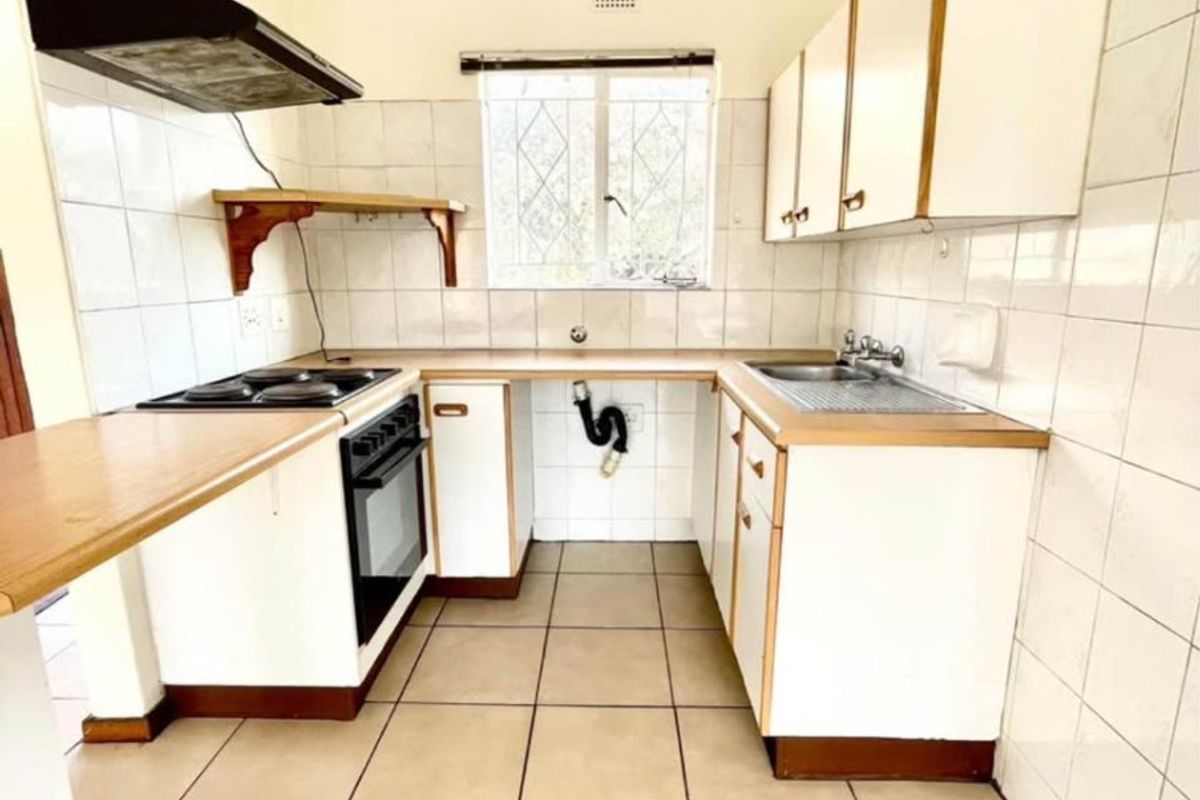 A functional kitchen featuring built-in cabinetry, laminate countertops, a built-in oven with hob, and tiled finishes throughout.
