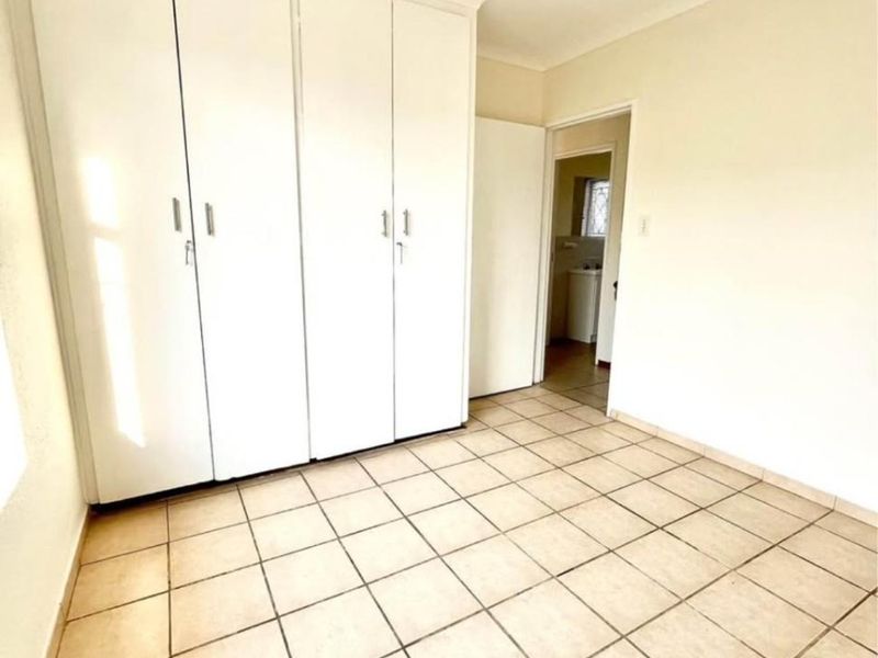 A bright, empty bedroom featuring neutral tiled flooring and ample built-in cupboard storage, offering a clean canvas for personalization.