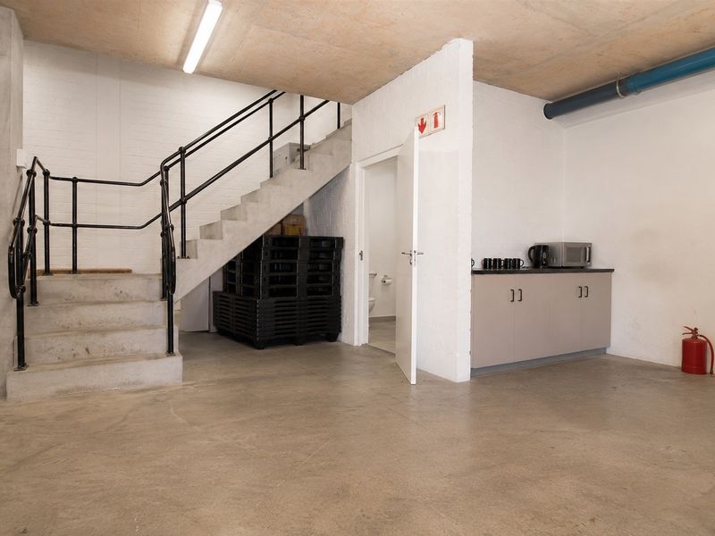 A functional utility space featuring a concrete staircase, built-in cabinetry, and industrial-style finishes, suitable for storage or office support.
