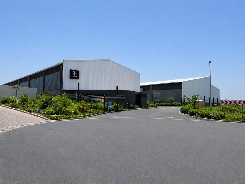 Modern commercial warehouse facility featuring metal cladding, paved access, and landscaped grounds with secure perimeter fencing.