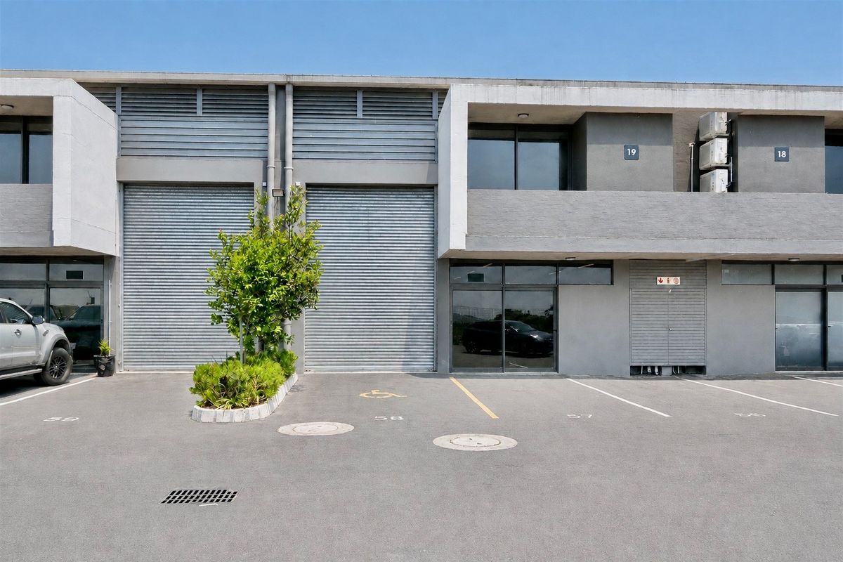 Front elevation of a commercial industrial unit featuring roller shutter doors, dedicated parking bays, and modern concrete facade finishes.