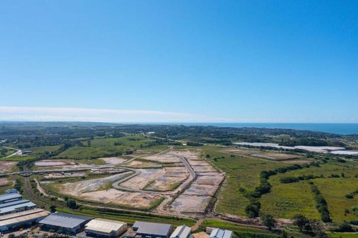 Aerial view of a developing commercial or residential land parcel featuring established road infrastructure and surrounding coastal landscape.