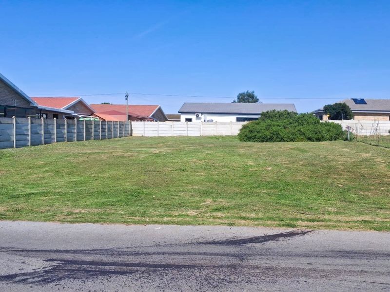 A level, vacant residential plot featuring a grass lawn and enclosed by precast concrete boundary walls in a suburban neighborhood.