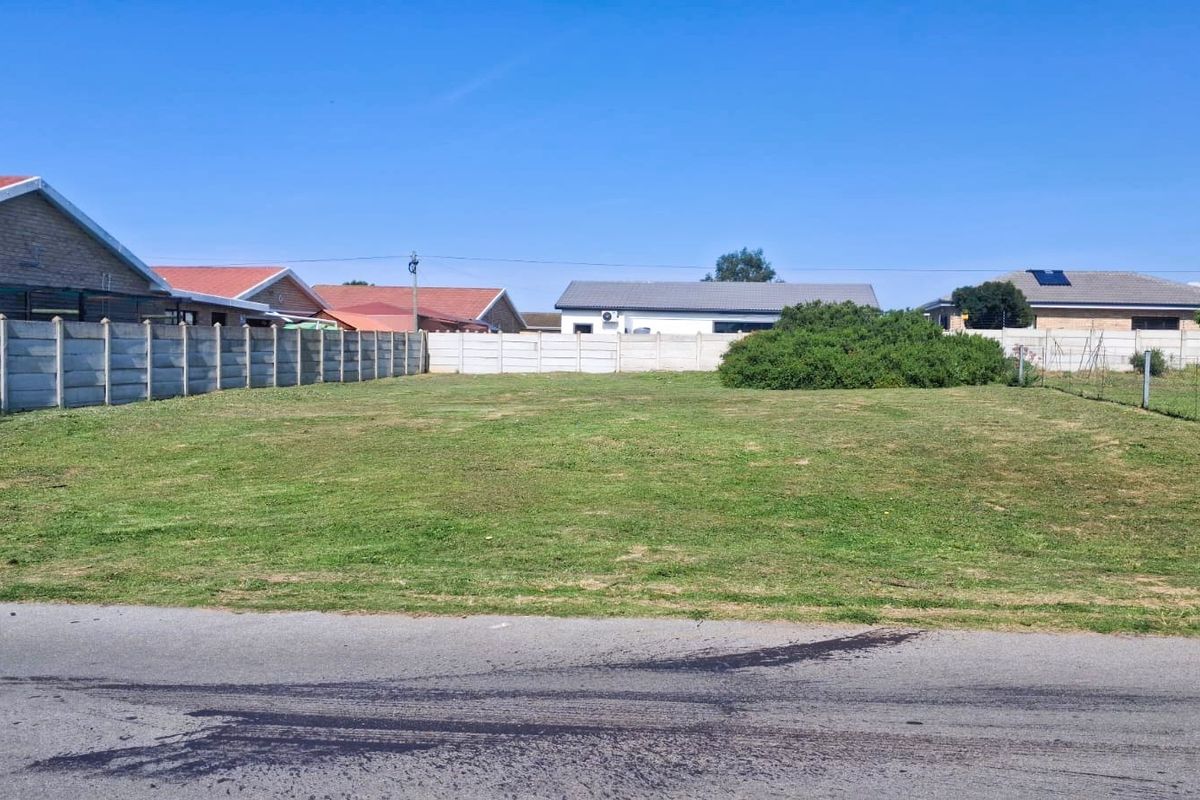 A level, vacant residential plot featuring a grass lawn and enclosed by precast concrete boundary walls in a suburban neighborhood.