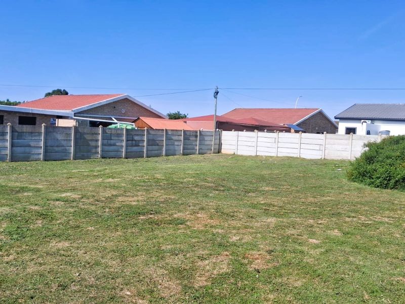 A level, grassed residential plot enclosed by precast concrete boundary walls, offering a clear space for potential development.