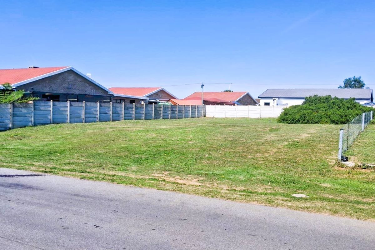 A vacant residential plot featuring a level grass surface, enclosed by precast concrete boundary walls and wire fencing, with direct street access.