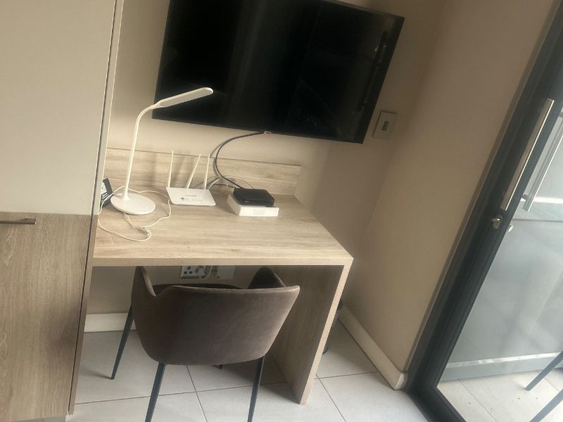 A compact bedroom area featuring a built-in desk, integrated cabinetry, and a sliding glass door providing access to an outdoor space.