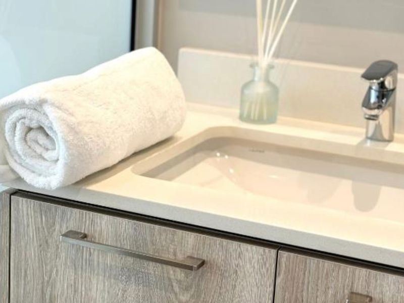 A modern bathroom vanity featuring a stone countertop, undermount sink, and contemporary chrome mixer tap with wood-grain cabinetry.