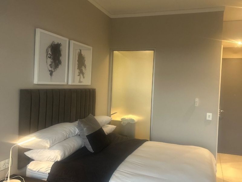 A well-maintained bedroom featuring neutral wall tones, tiled flooring, and direct access to an en-suite bathroom.
