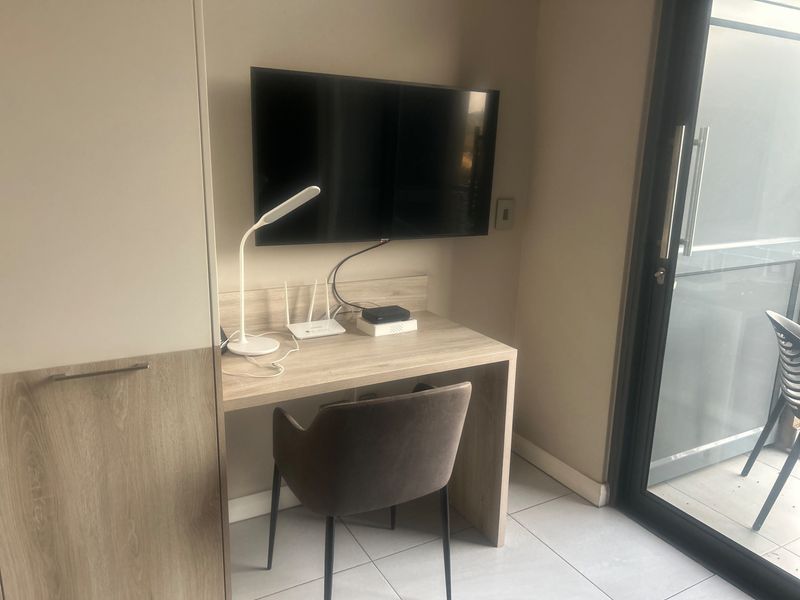 A functional bedroom area featuring a built-in desk, integrated cabinetry, and a sliding glass door providing access to an outdoor space.