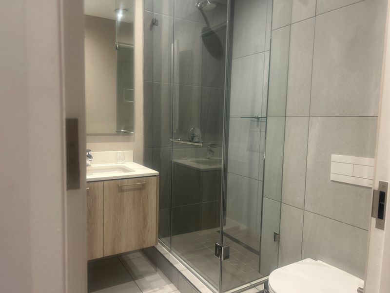 Modern bathroom featuring a wall-mounted vanity, glass-enclosed shower with rain head, and a wall-hung toilet with concealed cistern.