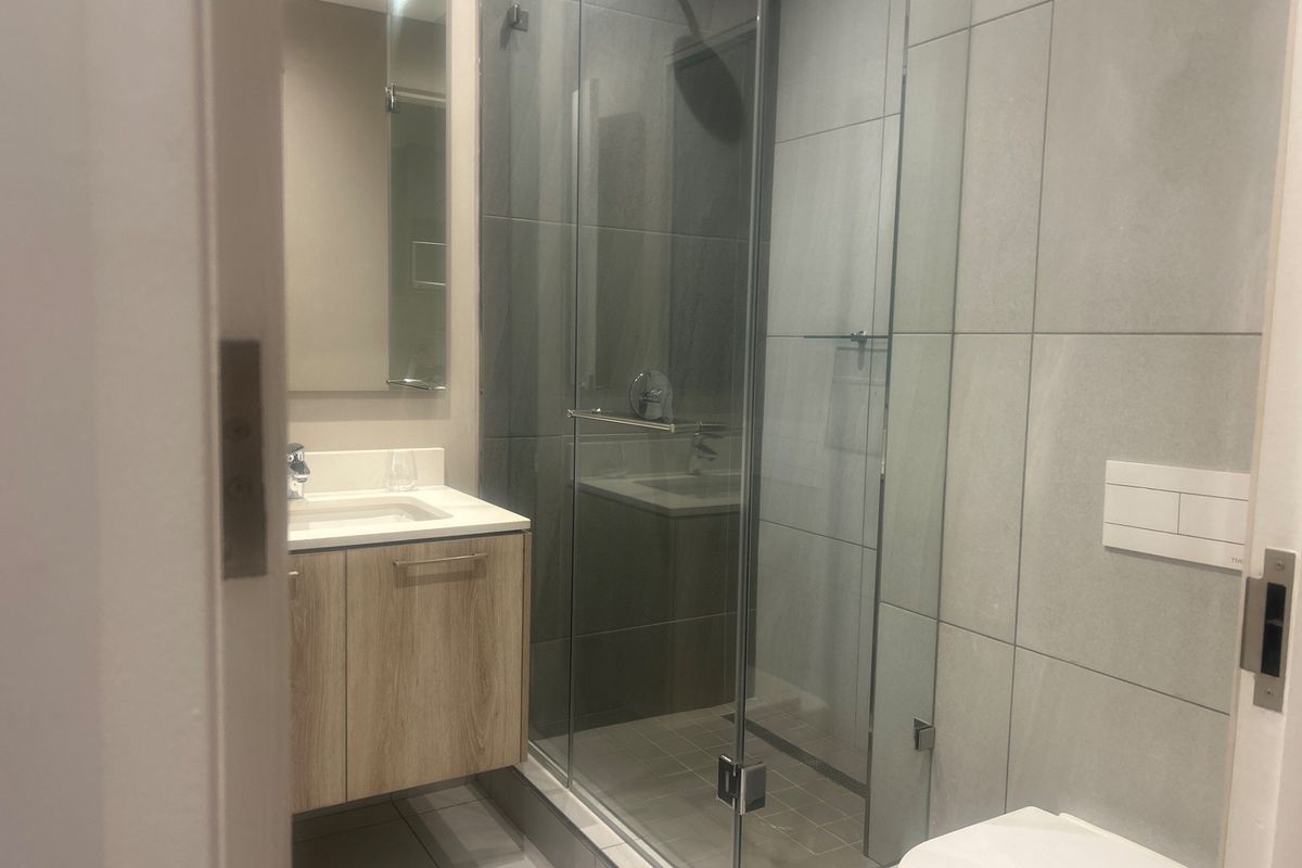 Modern bathroom featuring a wall-mounted vanity, glass-enclosed shower with rain head, and a wall-hung toilet with concealed cistern.