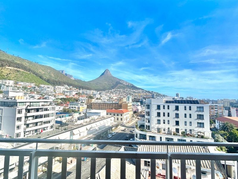 Elevated view from a balcony overlooking the urban landscape with a prominent mountain peak in the background.
