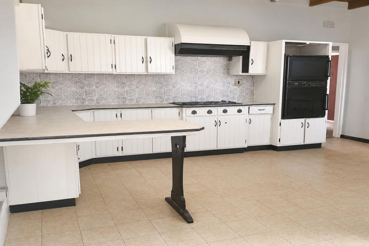 Spacious kitchen featuring white cabinetry, built-in oven, gas hob, extractor fan, and tiled flooring, offering a functional layout ready for modern updates.