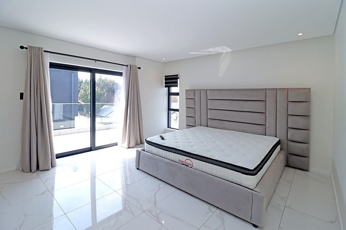 Modern bedroom featuring large format marble-look floor tiles, recessed lighting, and a sliding glass door providing access to an outdoor balcony area.