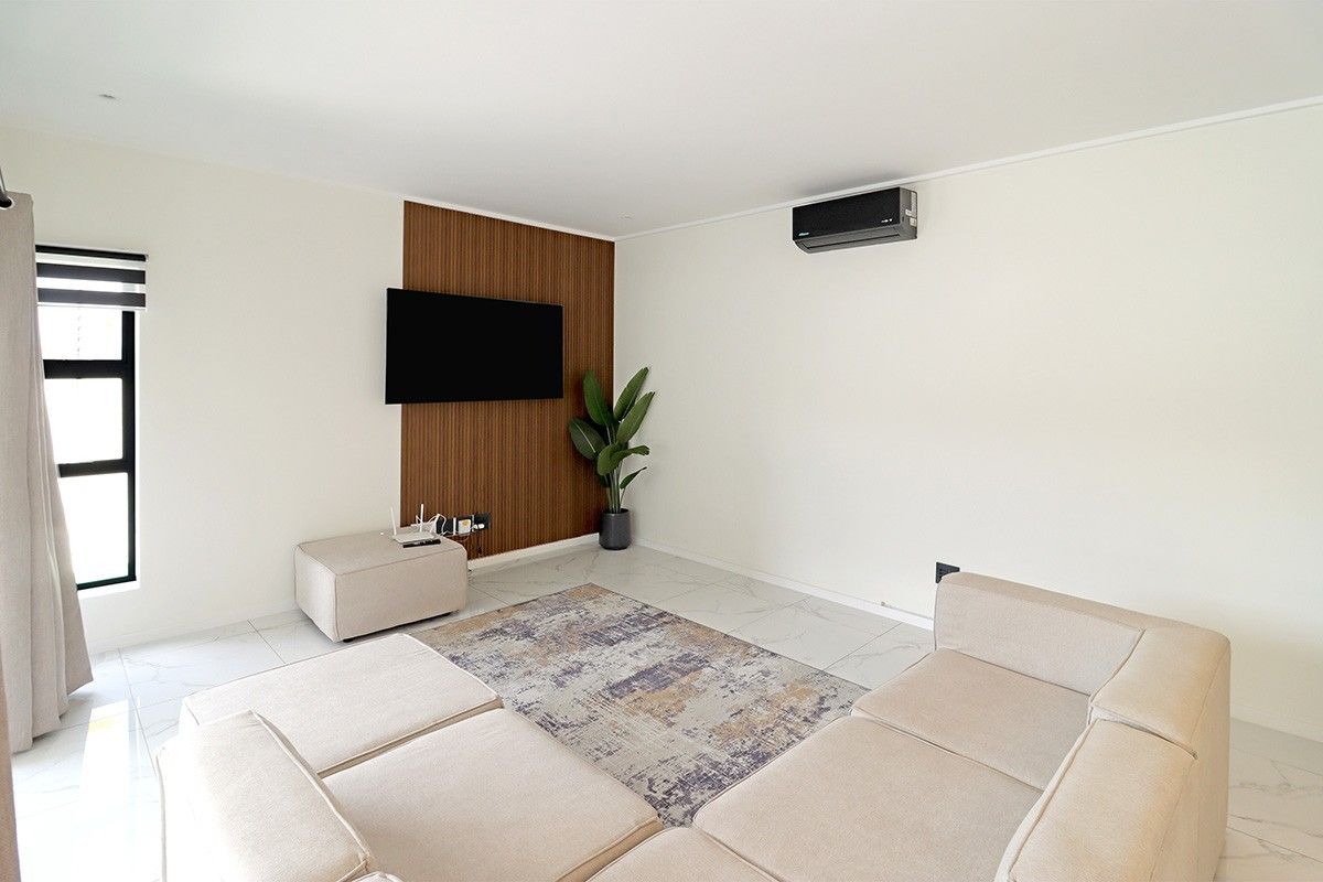 A bright living room featuring tiled flooring, a wood-look feature wall, and a wall-mounted air conditioning unit.