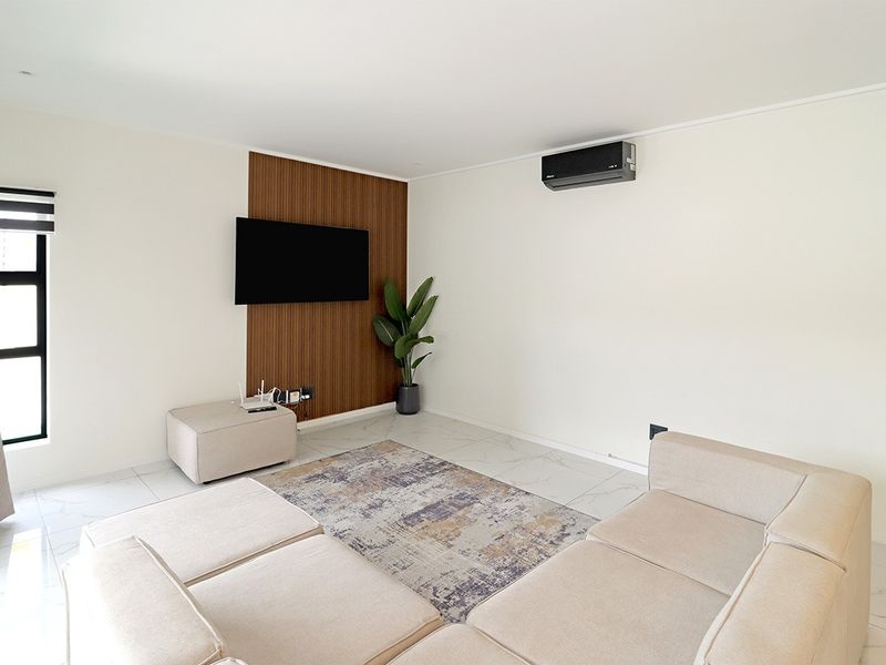 A bright living room featuring tiled flooring, a wood-look feature wall, and a wall-mounted air conditioning unit.
