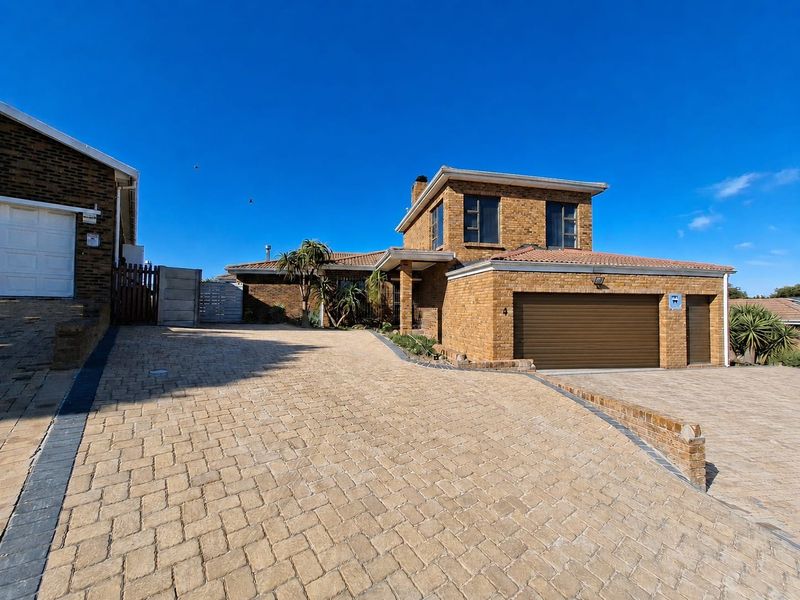 Front view of a double-story brick house featuring a spacious paved driveway, double garage, and well-maintained exterior finishes.