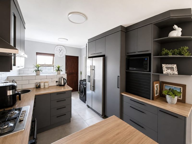 Modern kitchen featuring dark grey cabinetry, timber laminate countertops, subway tile backsplash, and integrated appliances including a gas cooktop and built-in microwave.