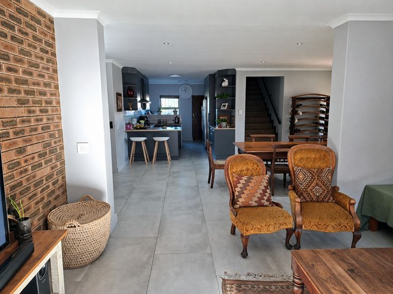 Spacious open-plan living and kitchen area featuring modern tiled floors, an exposed brick feature wall, and a functional kitchen with island seating.