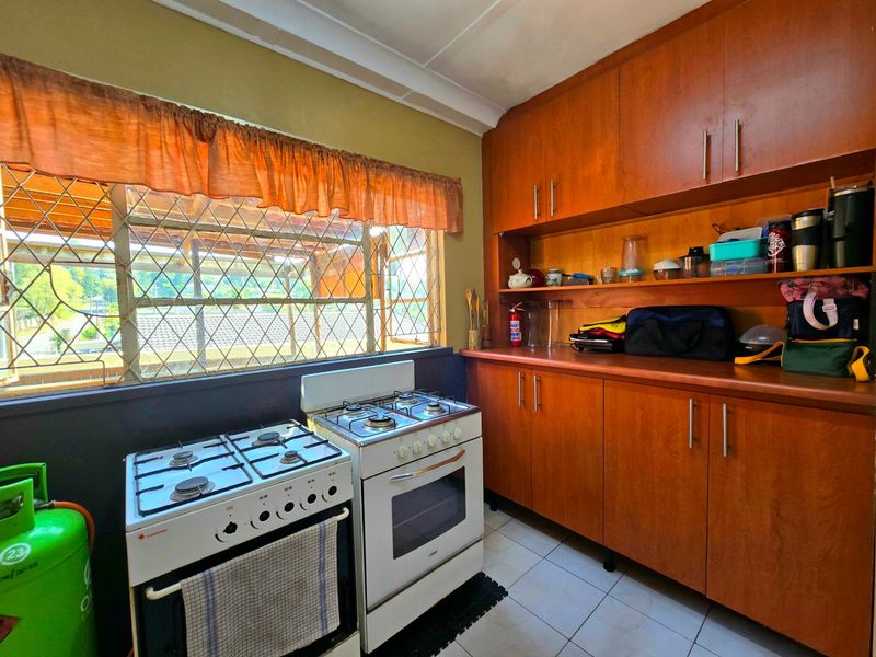 A functional kitchen featuring wooden cabinetry, tiled flooring, and a gas stove, offering a practical layout with potential for modern updates.
