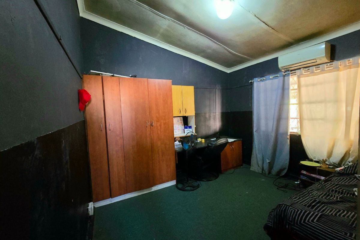 A bedroom featuring built-in cabinetry, a split-system air conditioner, and carpet flooring. The room requires cosmetic updates, including ceiling repairs and fresh paint.