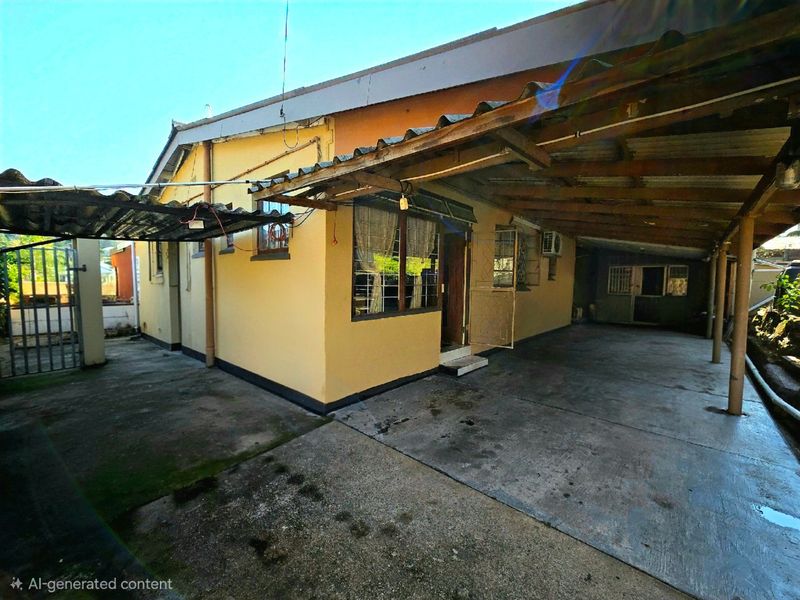 Rear exterior view of the townhouse featuring a concrete driveway, covered patio area, and security bars on windows.