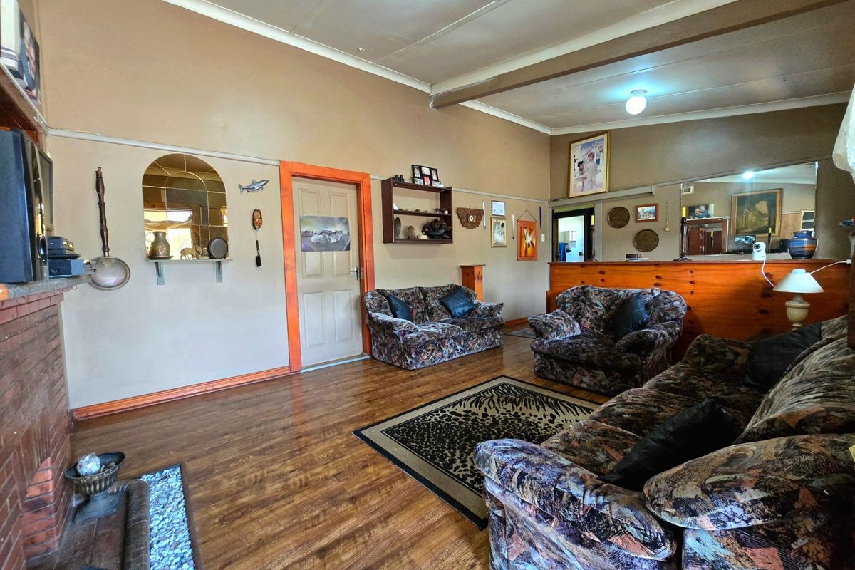 Spacious living room featuring a brick fireplace, laminate flooring, and a built-in timber partition, offering a traditional layout with potential for modern updates.