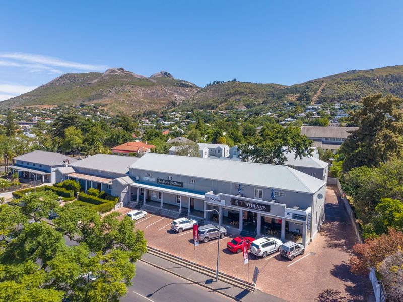 Aerial view of a commercial office complex featuring paved parking, covered walkways, and mountain views in a well-maintained setting.