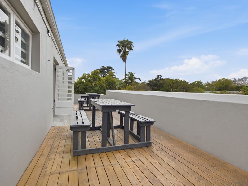 A well-maintained outdoor timber deck balcony featuring a solid parapet wall and direct access to the office interior via a french door.
