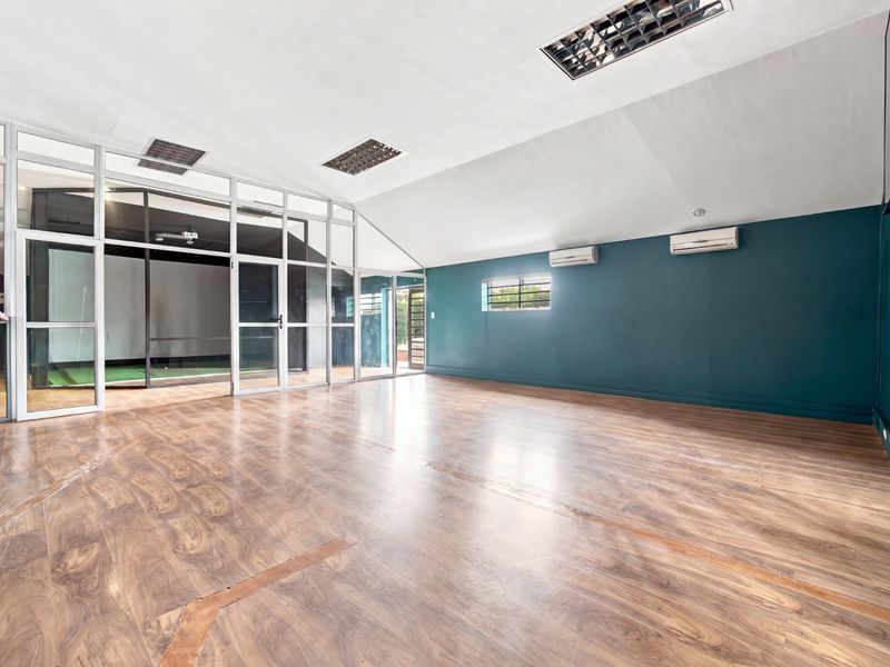 Spacious, empty office area featuring laminate flooring, recessed lighting, split-system air conditioning, and a modern glass partition wall.