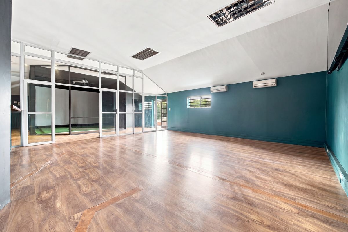 Spacious, empty office area featuring laminate flooring, recessed lighting, split-system air conditioning, and a modern glass partition wall.