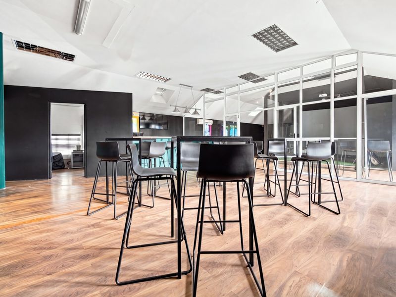Modern office space featuring laminate flooring, glass partition walls, and recessed ceiling lighting with skylights for natural illumination.