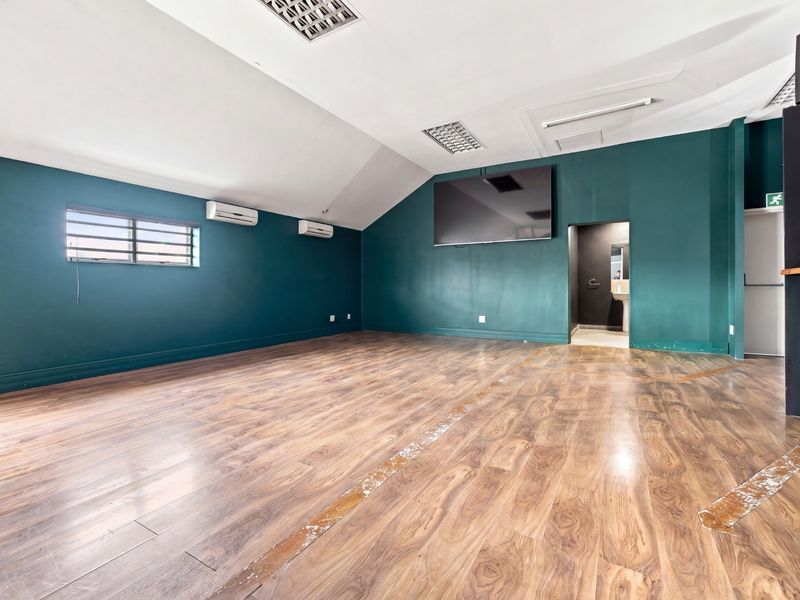 Spacious open-plan office area featuring laminate flooring, recessed ceiling lighting, and dual split-system air conditioning units.