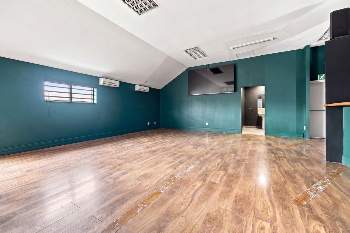 Spacious open-plan office area featuring laminate flooring, recessed ceiling lighting, and dual split-system air conditioning units.