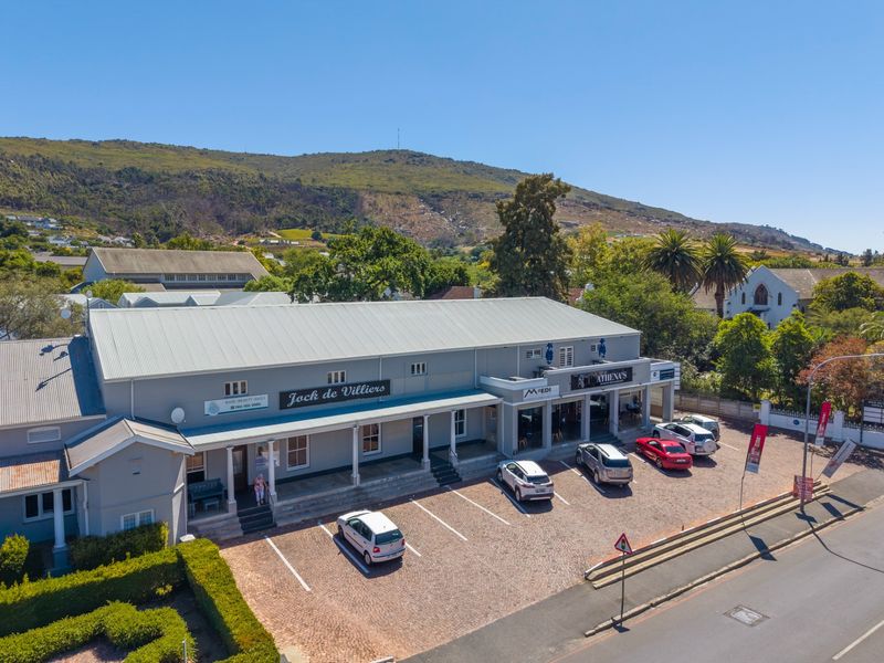 Aerial view of a commercial office building featuring a metal roof, covered veranda, and dedicated paved parking area in a scenic location.