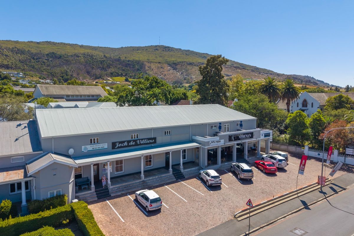 Aerial view of a commercial office building featuring a metal roof, covered veranda, and dedicated paved parking area in a scenic location.