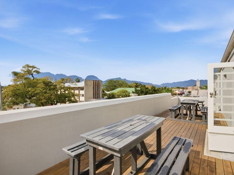 An elevated outdoor balcony featuring timber decking, a solid parapet wall, and scenic mountain views, providing an ideal space for outdoor office breaks.