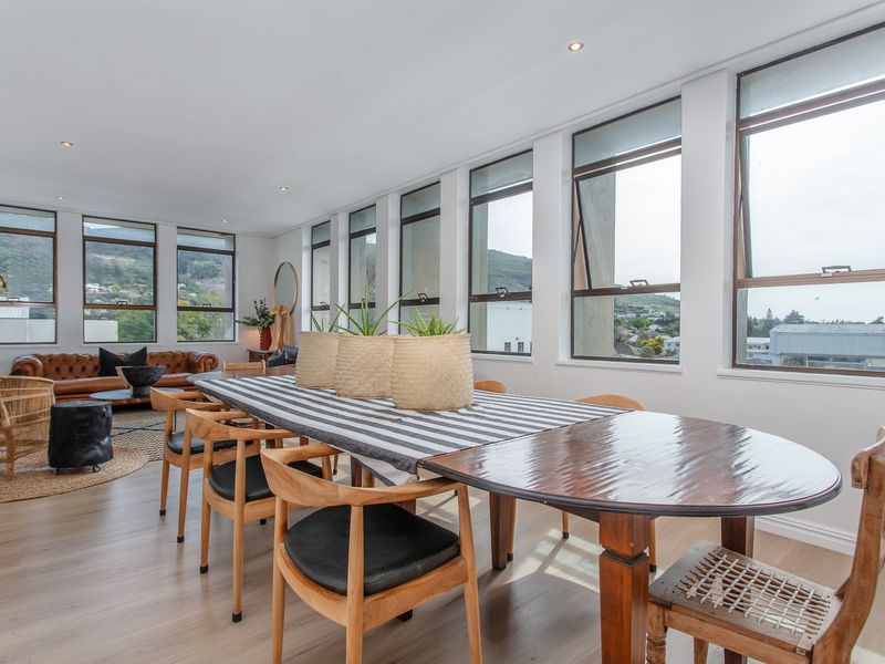 Spacious open-plan living and dining area featuring light laminate flooring, recessed downlights, and expansive windows offering abundant natural light and scenic views.
