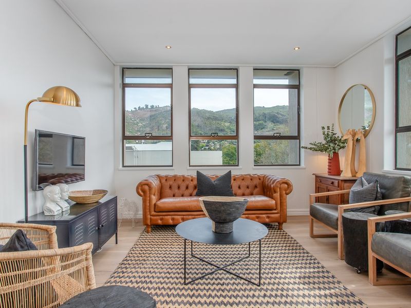 A bright and well-maintained living room featuring large windows with scenic mountain views, recessed lighting, and modern laminate flooring.