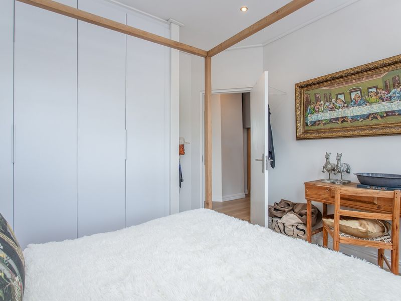 A well-maintained bedroom featuring floor-to-ceiling built-in cupboards, recessed lighting, and neutral finishes, providing a clean and functional living space.