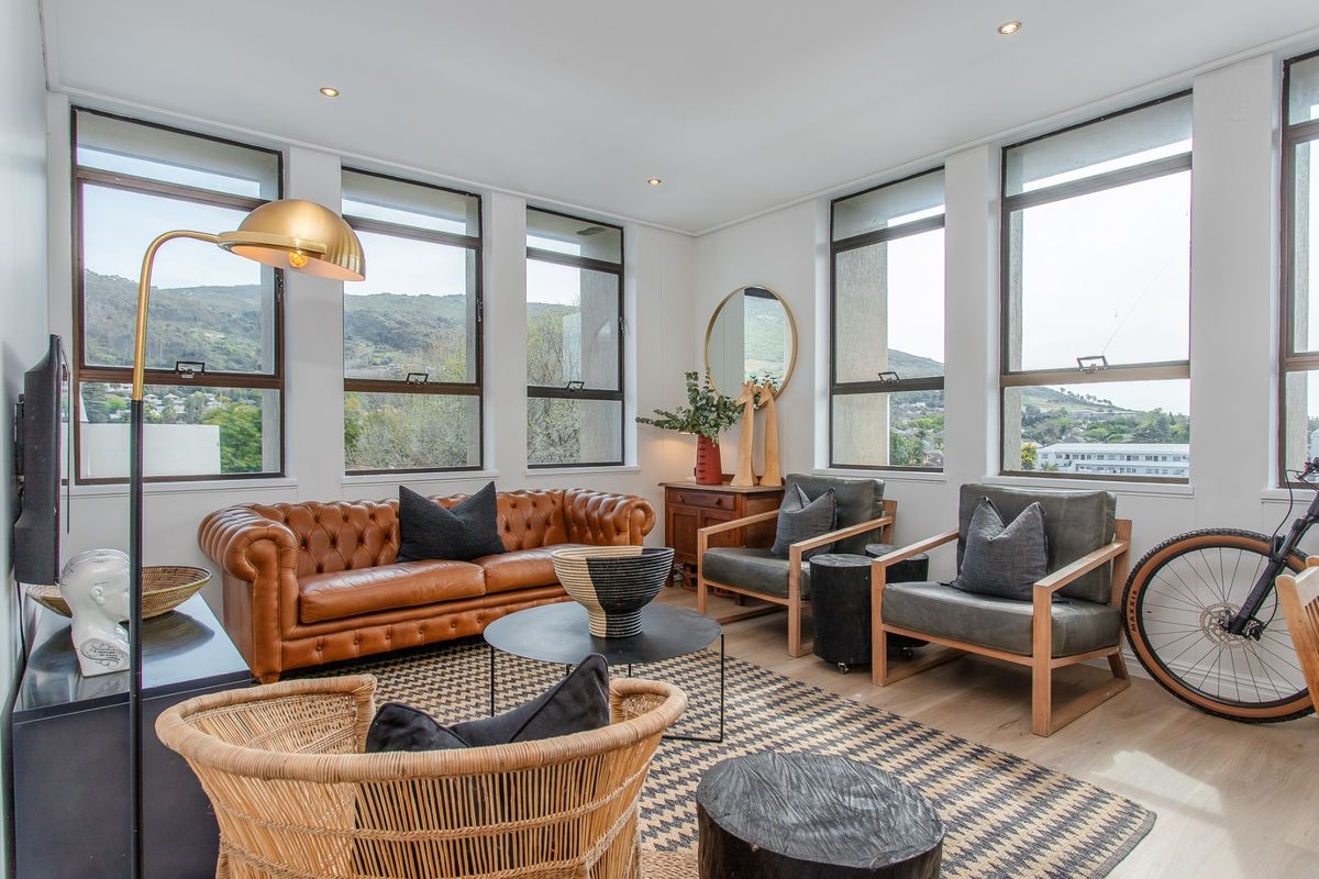 Bright and airy living room featuring large windows with mountain views, recessed downlighting, and light timber flooring.