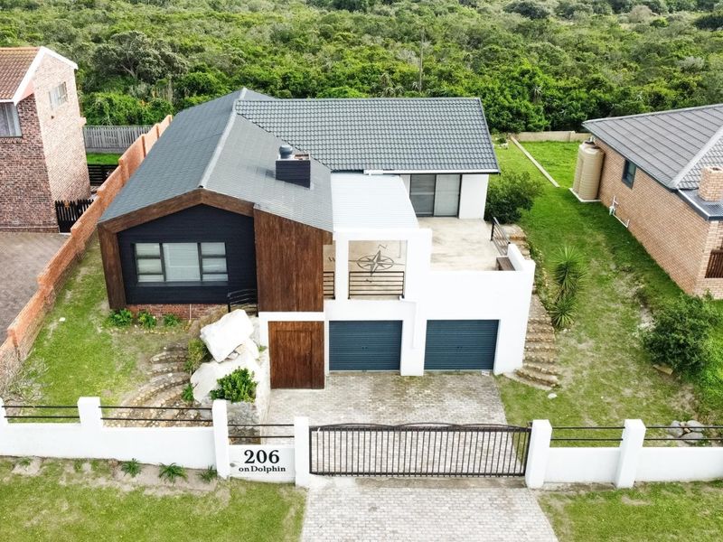Aerial view of a modern residential property featuring a double garage, paved driveway, secure boundary wall, and a balcony with a compass design.