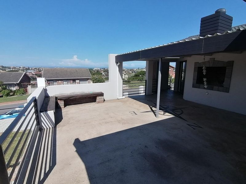 Spacious covered balcony featuring a built-in braai, concrete flooring with compass design, and panoramic neighborhood views.