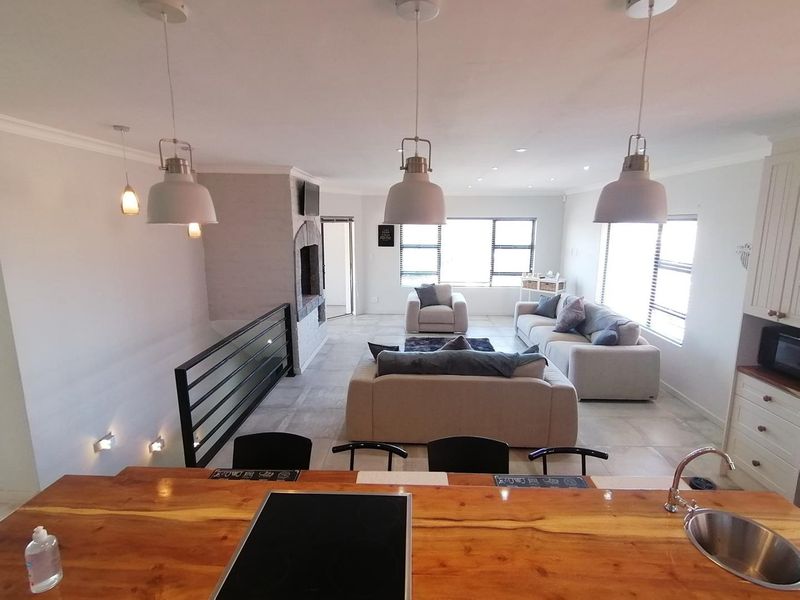 Spacious open-plan living area featuring a kitchen island with a built-in hob, fireplace, and modern tiled flooring, creating a seamless flow between spaces.
