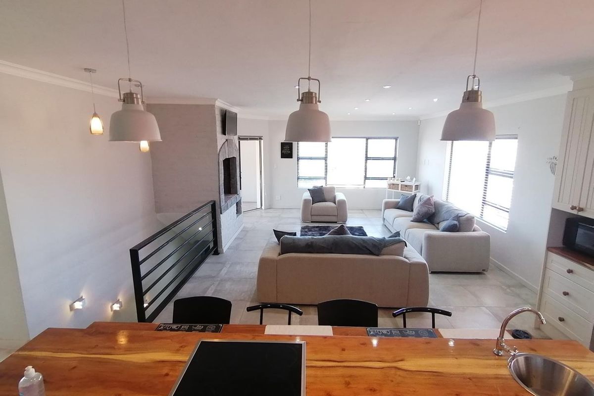 Spacious open-plan living area featuring a kitchen island with a built-in hob, fireplace, and modern tiled flooring, creating a seamless flow between spaces.