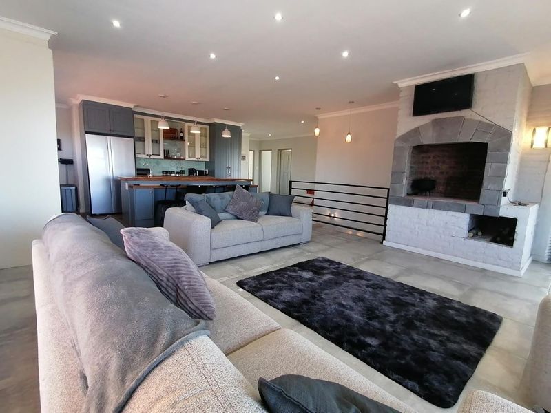 Spacious open-plan living area featuring a large built-in stone fireplace, modern kitchen with island, and tiled flooring throughout.