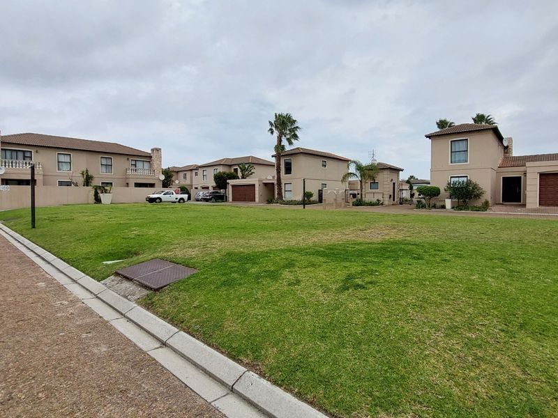 A wide-angle view of a townhouse complex featuring multiple residential units, paved driveways, and a shared green lawn area.