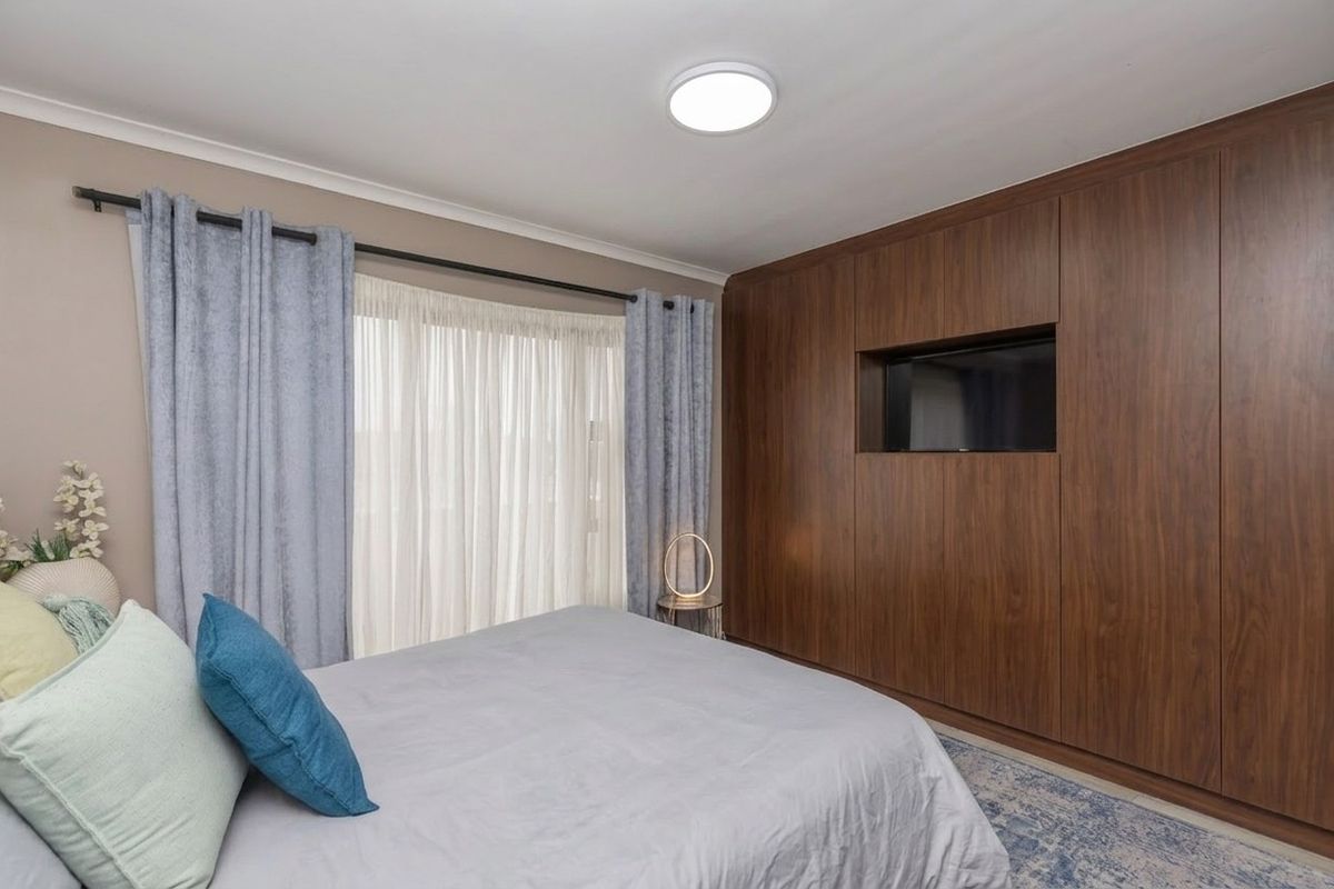 A well-maintained bedroom featuring extensive floor-to-ceiling wood-finish built-in cabinetry with an integrated television recess.
