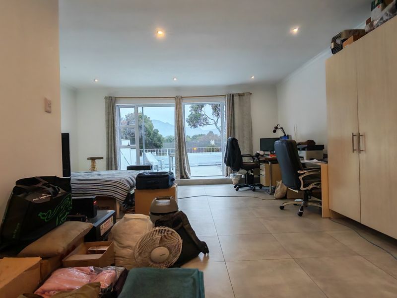 Open-plan living area featuring tiled flooring, recessed lighting, and large sliding glass doors leading to an outdoor balcony.